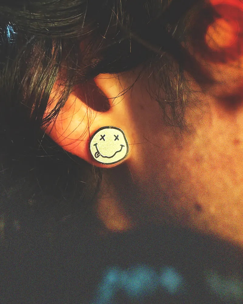 Side photo of man wearing a shiny silver classic "Smiley Face" Nirvana Earring.