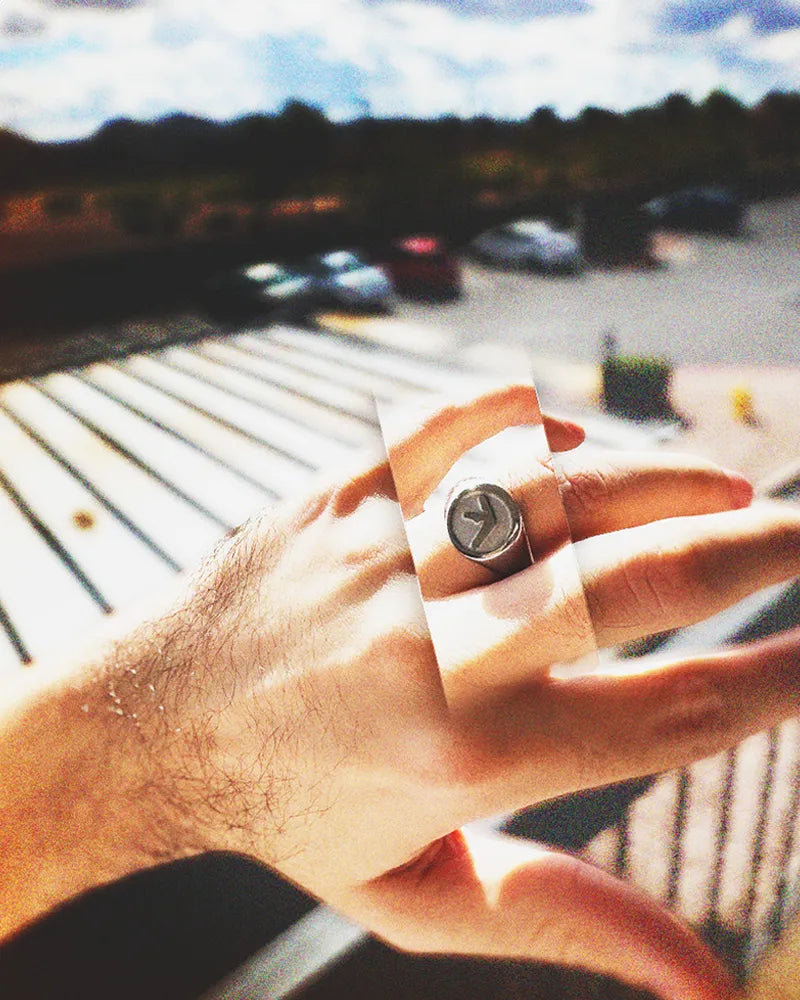 Hand wearing shiny stainless steel aphex twin ring on a sunny day