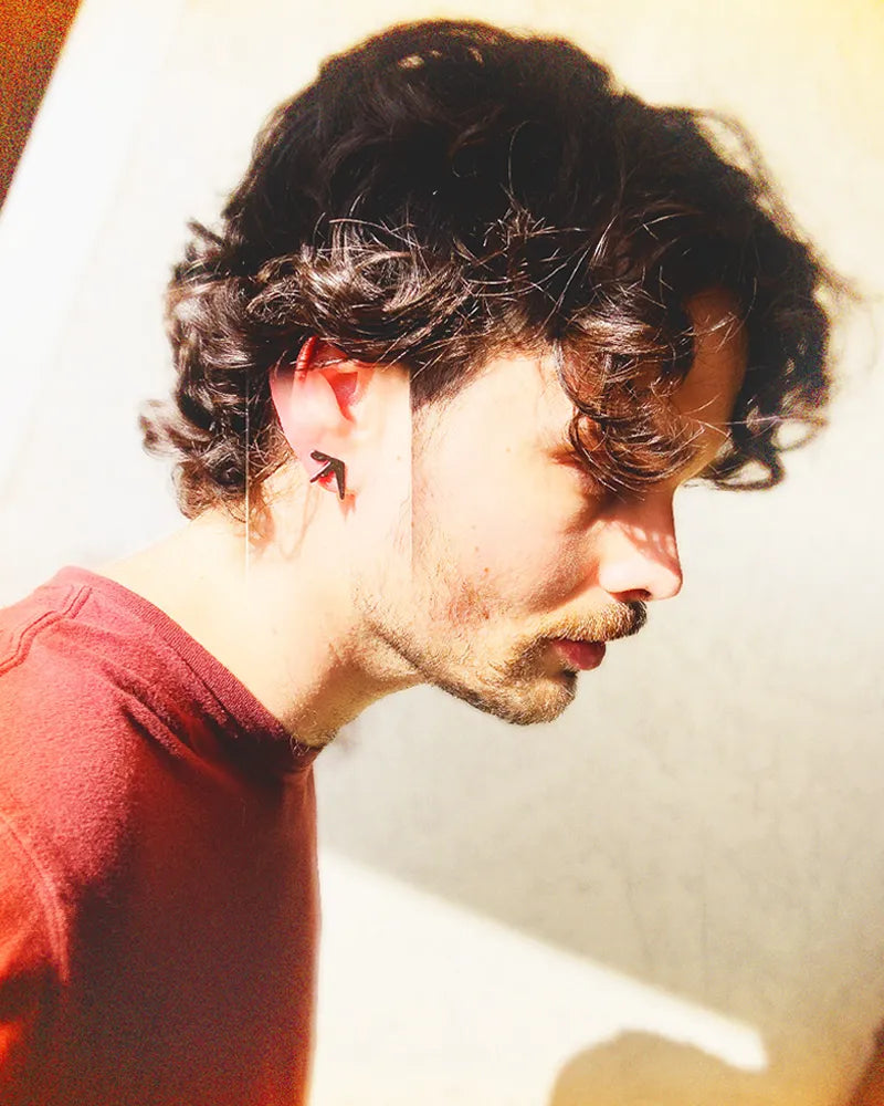 Man wearing a 0.5-inch stainless steel earring inspired by Aphex Twin