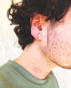 Close-up of a man wearing a 0.5-inch stainless steel earring inspired by Death Grips' Money Store