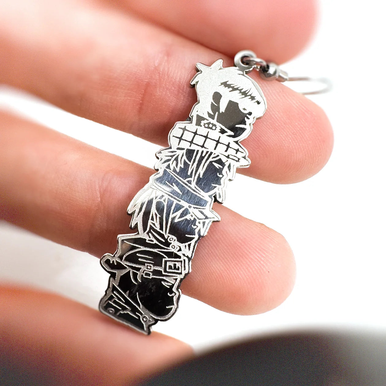 Hand holding hand-made stainless steel dangly earrings featuring the iconic Demon Days album design by Gorillaz.