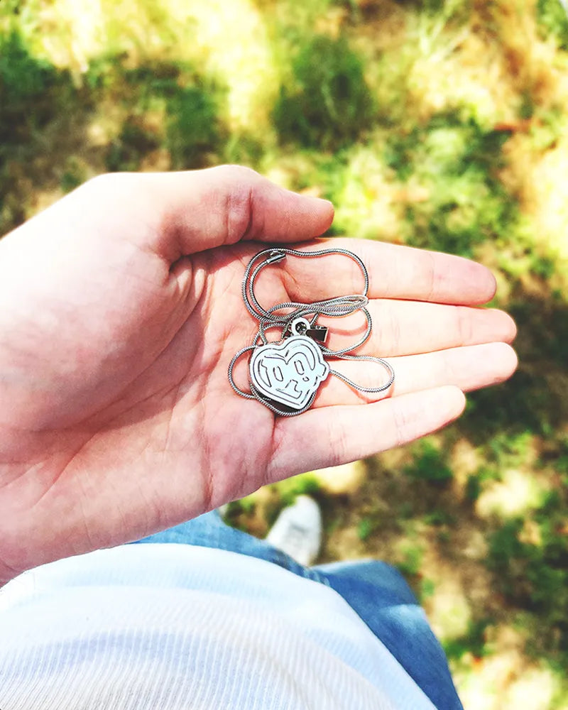 Hand holding a Drain Gang Love Pill necklace