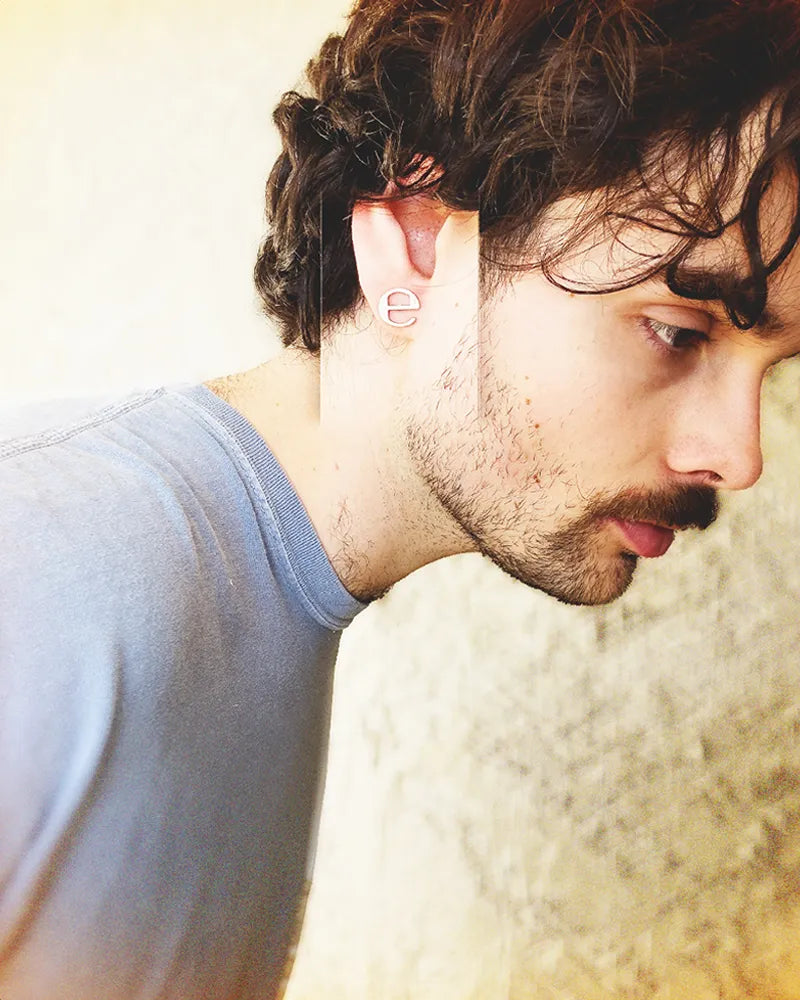 Man wearing a 0.5-inch stainless steel earring with Ecco2k 'E' logo