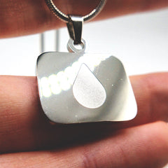 Lumon tear logo stainless steel necklace shown on a hand for size reference