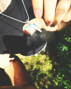 Man wearing and holding up a 1-inch stainless steel Aphex Twin necklace