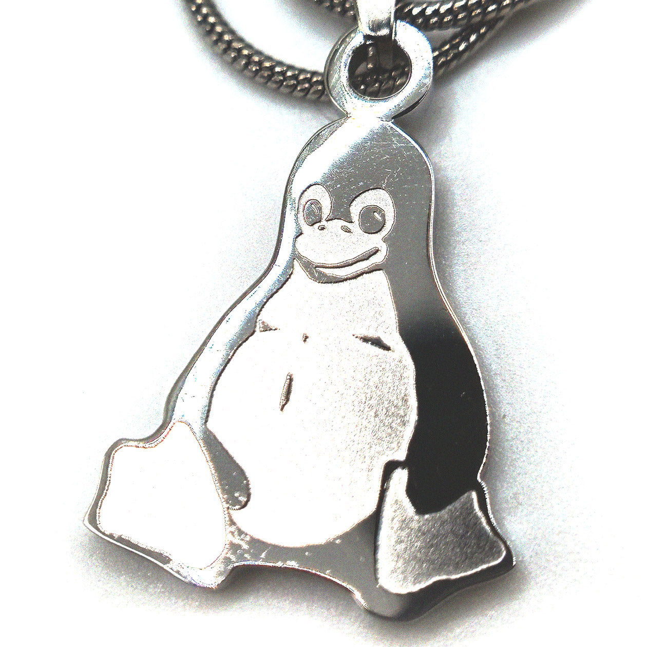 Stainless steel Tux penguin necklace displayed on a person’s fingers for size reference