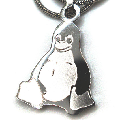 Stainless steel Tux penguin necklace displayed on a person’s fingers for size reference