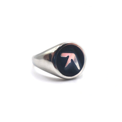 Stainless steel silver ring tilted to the side with an Aphex Logo on a black circular base