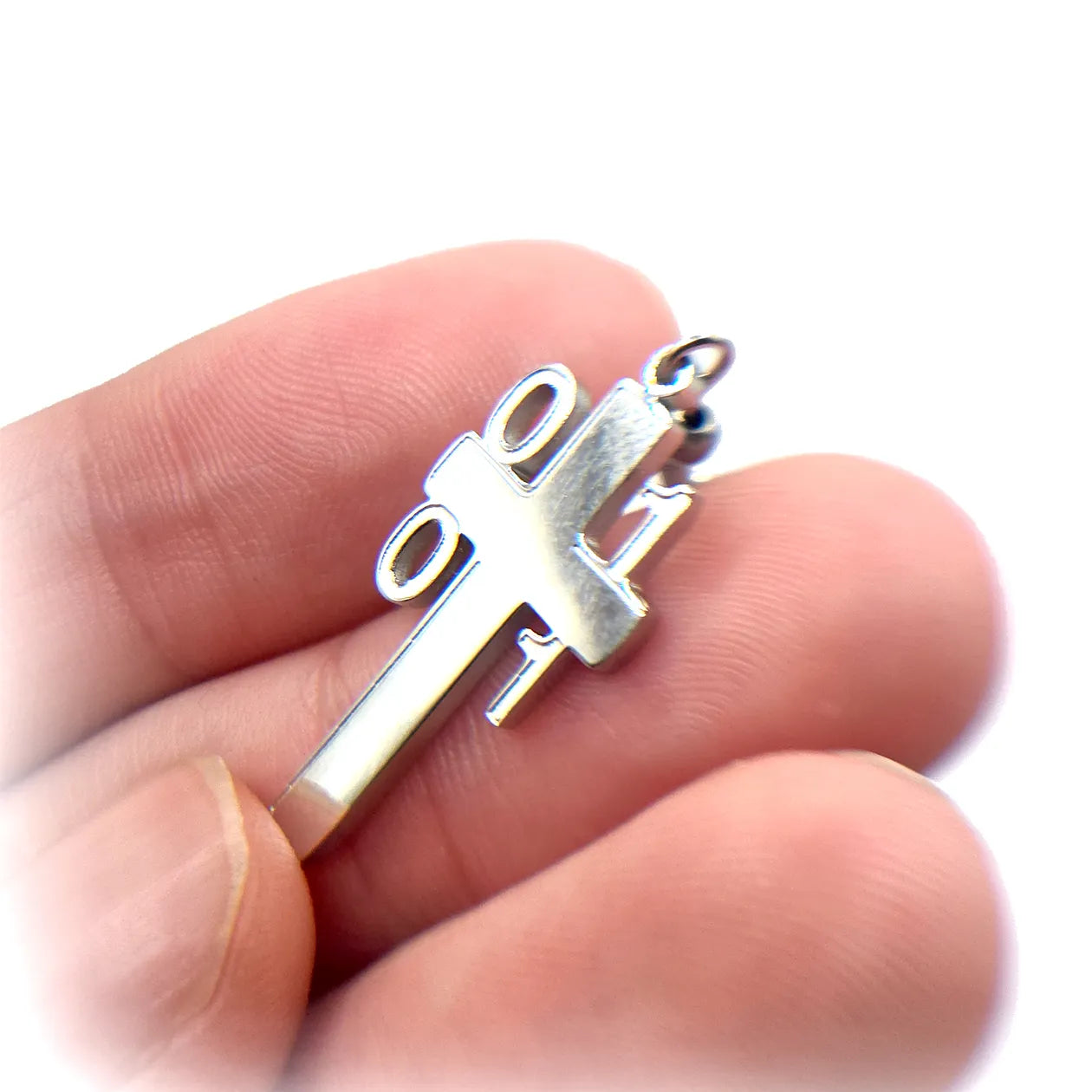 Hand holding a Binary Architect Cross Earring, highlighting the precision-cut stainless steel and unique binary code Christian cross design.