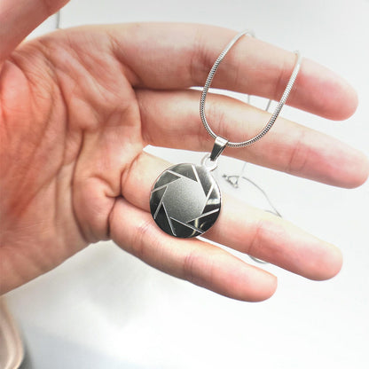 hand holding a stainless steel aperture science logo necklace from Portal 2